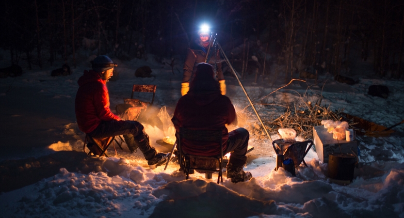 a group of people sit around a campfire in the snow